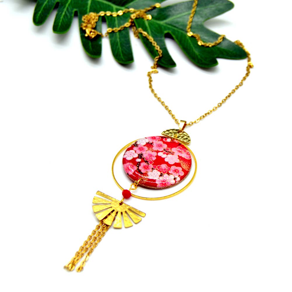 Necklace with a pink floral pendant and gold accents on a white background